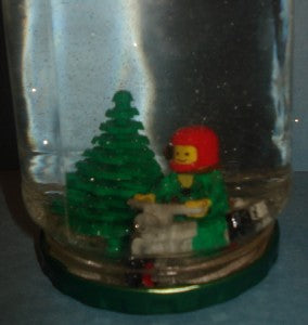 Snowglobe with a Christmas tree and lego Robin Hood riding a motorcycle in the snow.